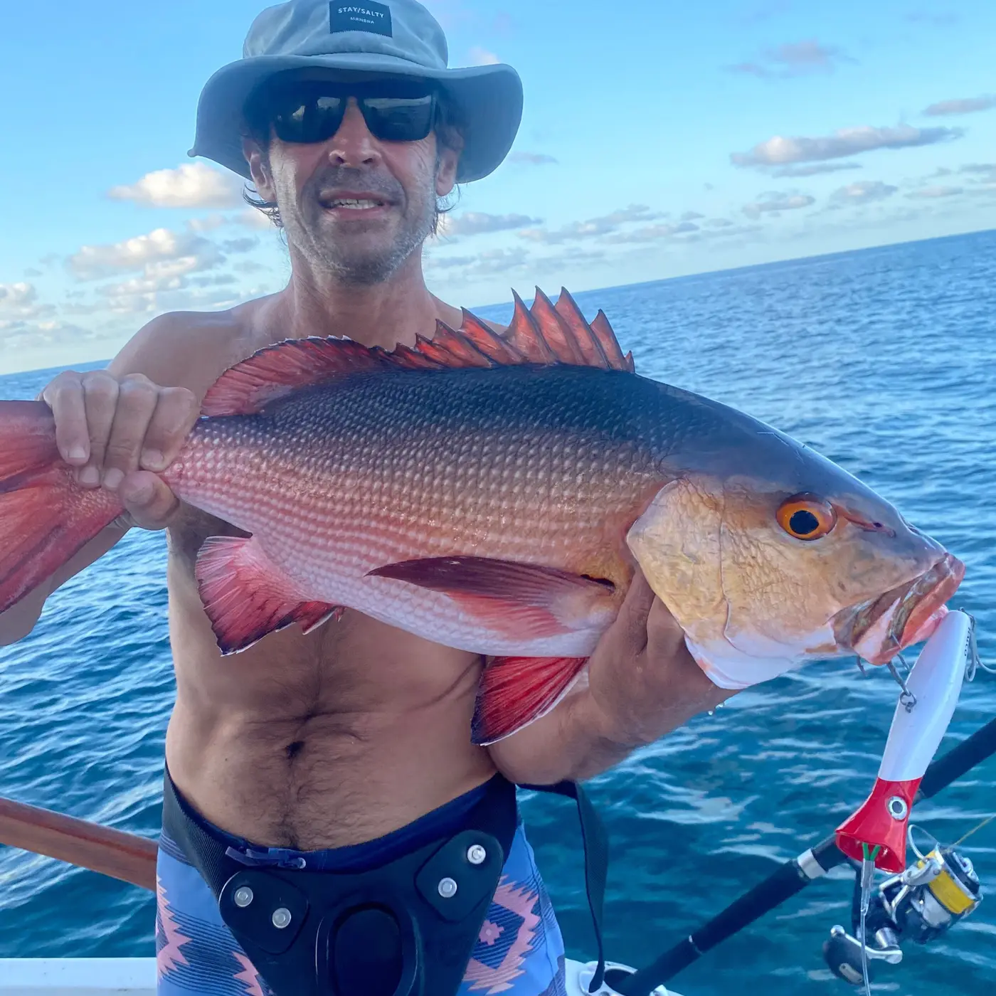 Angler holding a large red snapper caught reef fishing in the Seychelles