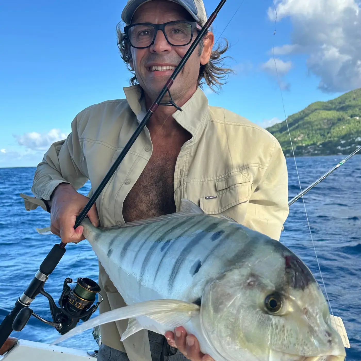 Angler holding a trevally with a Seychelles island in the background