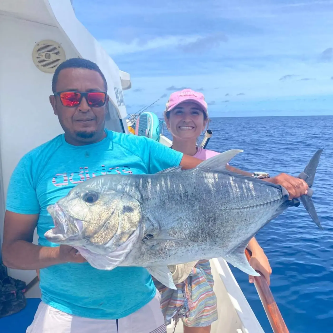 Two anglers holding a giant trevally caught popping in the Seychelles Outer Islands