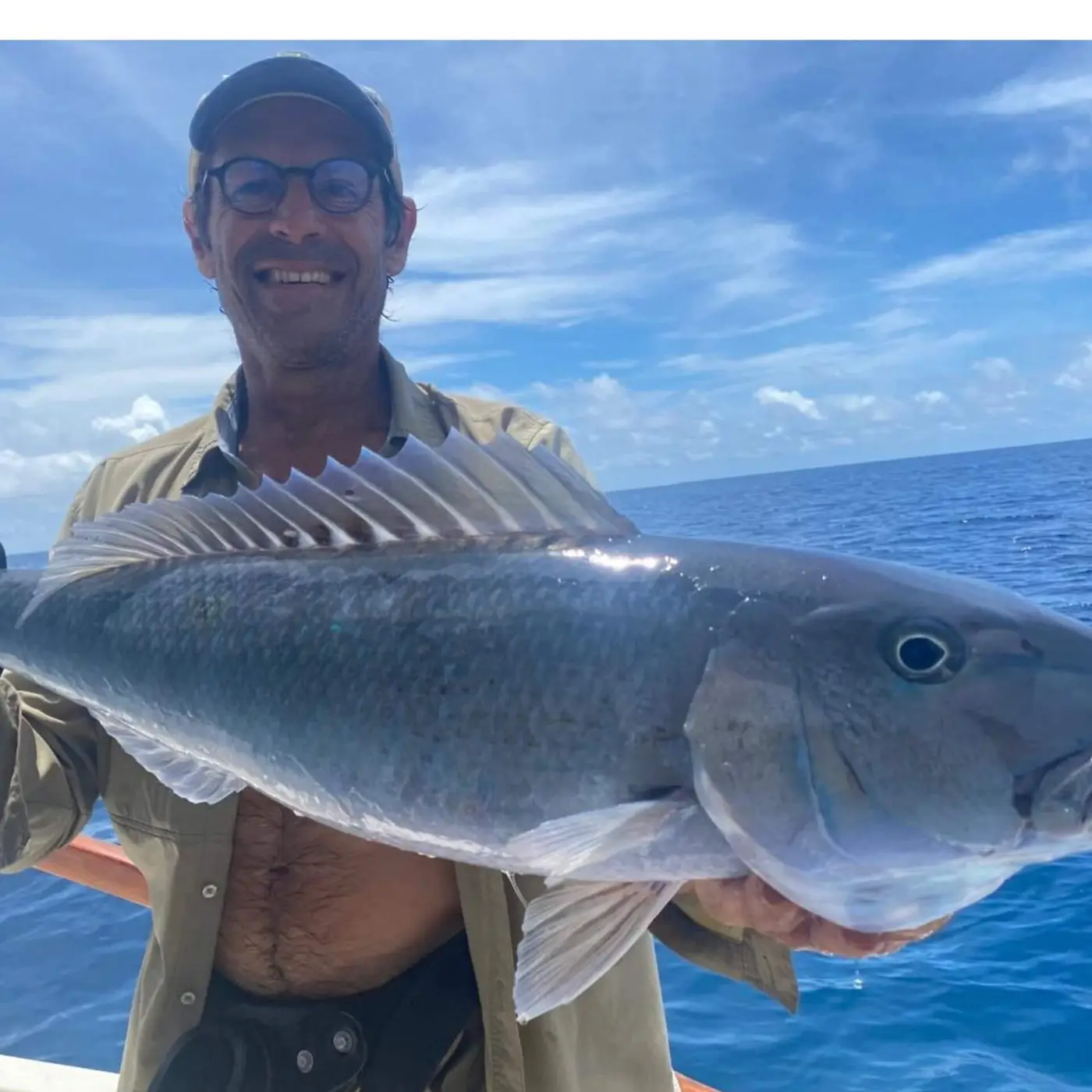 Angler holding a green jobfish caught on the reef