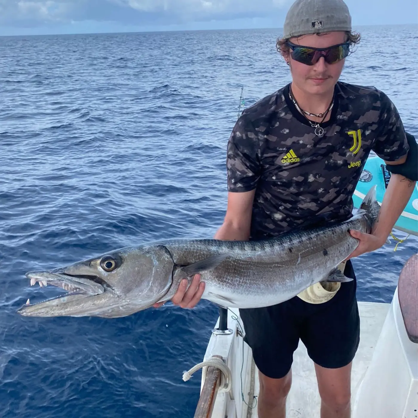 Angler holding a barracuda caught in the Seychelles Outer Islands